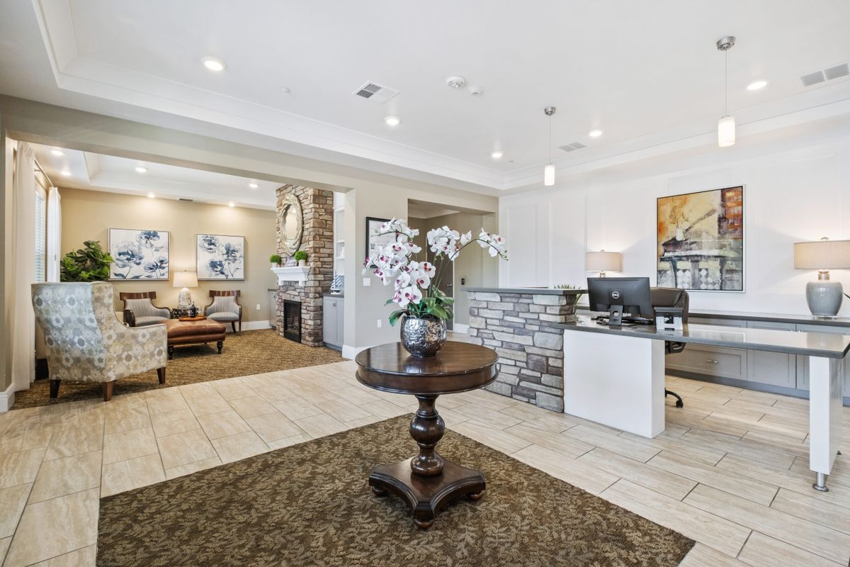 A modern lobby with a reception desk, elegant decor, and a central table adorned with flowers.