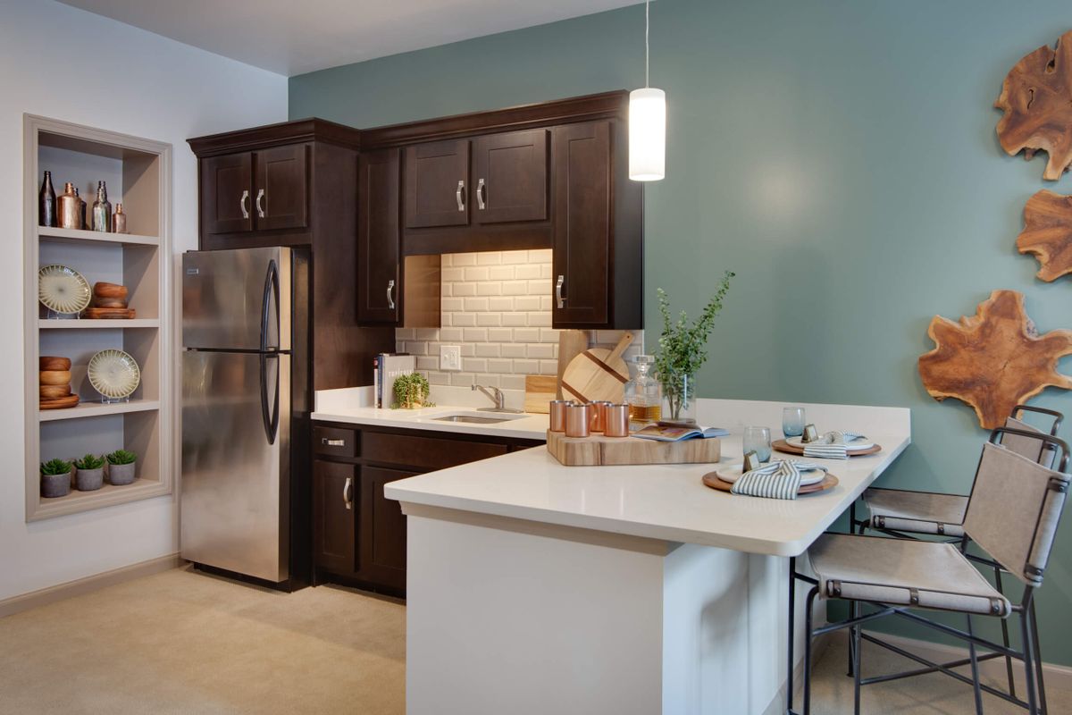 A modern kitchen with dark wood cabinets, stainless steel appliances, and a small island counter.