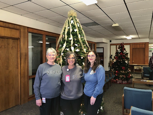Three women posing in front of a beautifully decorated Christmas tree.