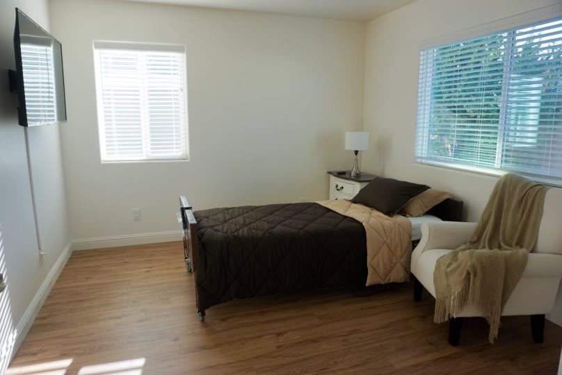 A minimalist bedroom with a single bed, lamp, and hardwood flooring.