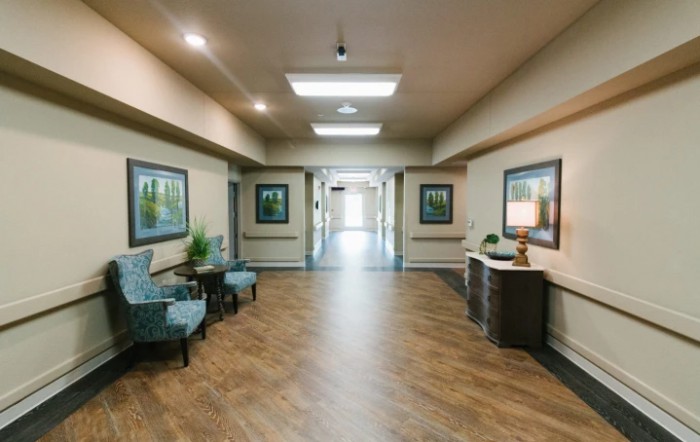 A well-decorated hallway with paintings, chairs, and wooden flooring.
