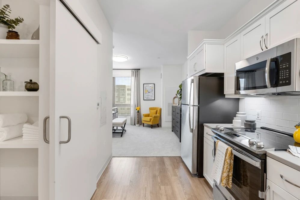 Modern apartment interior featuring an open kitchen leading to a cozy living area with a yellow chair.