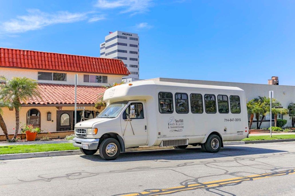 A white shuttle bus parked on a street with buildings in the background.