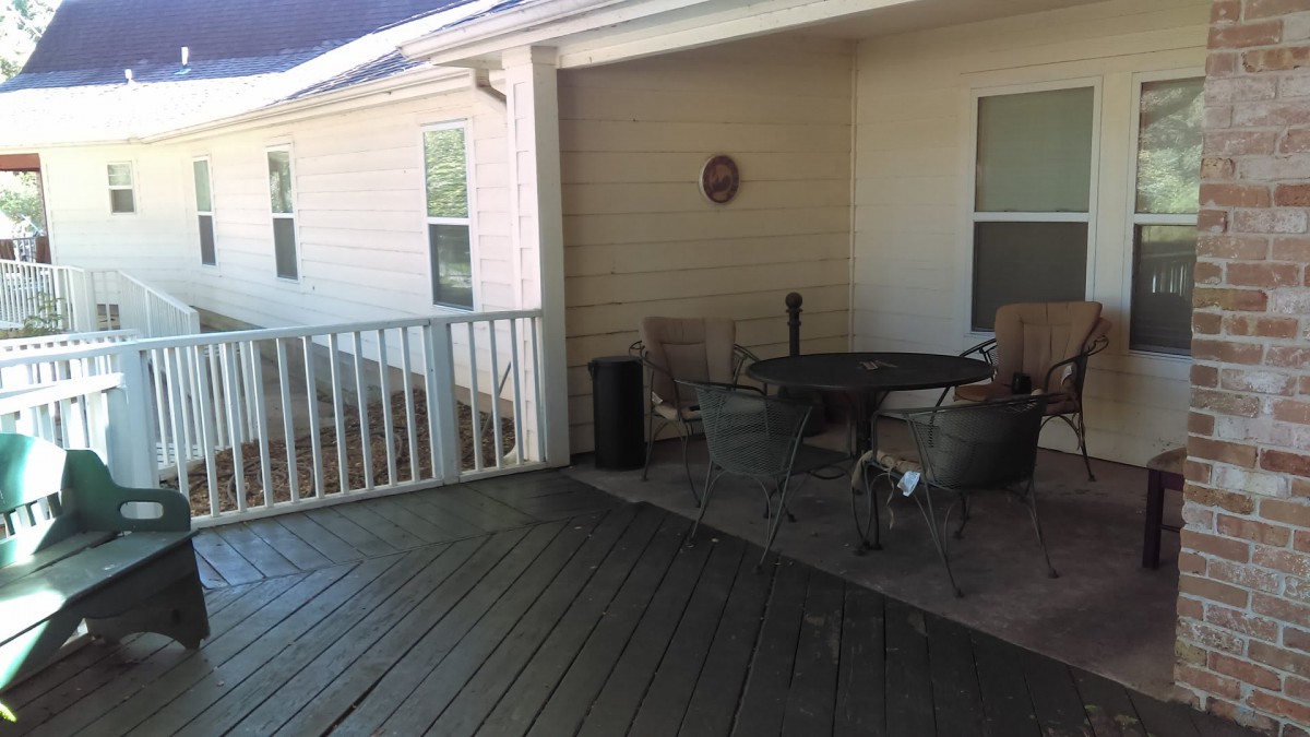 A cozy outdoor patio with a table and chairs set on a wooden deck.