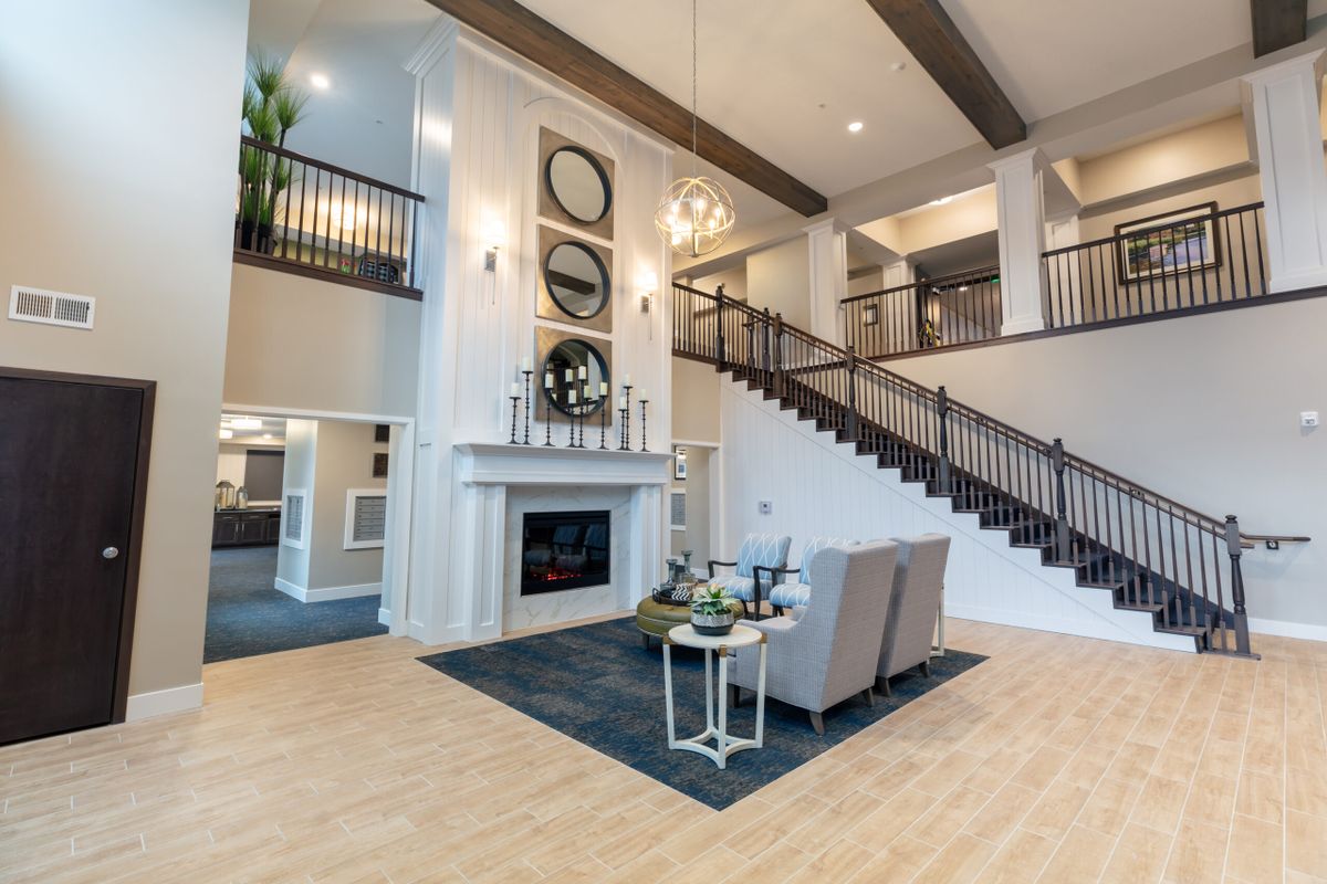Spacious living room with a modern design featuring a fireplace, elegant staircase, and high ceilings.
