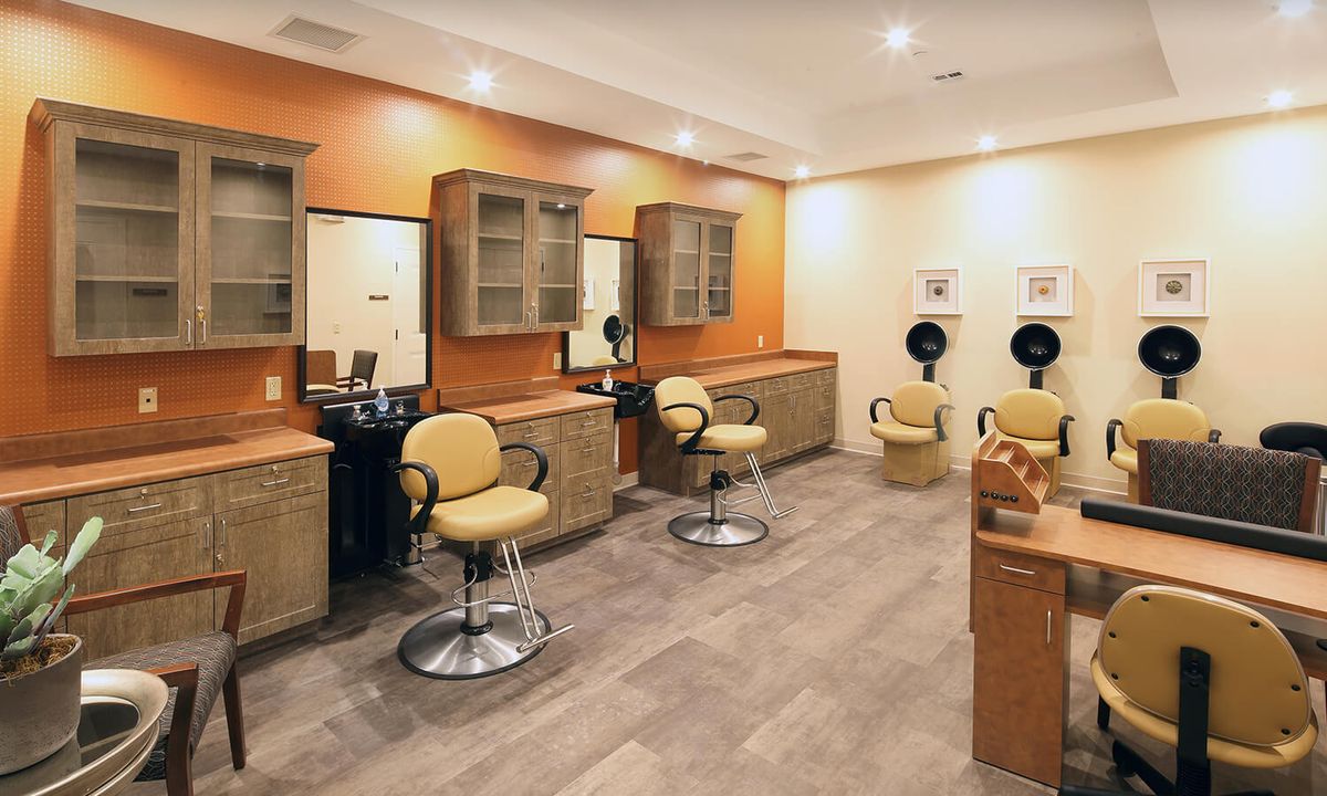 A modern salon interior featuring chairs, mirrors, and hairdryers.