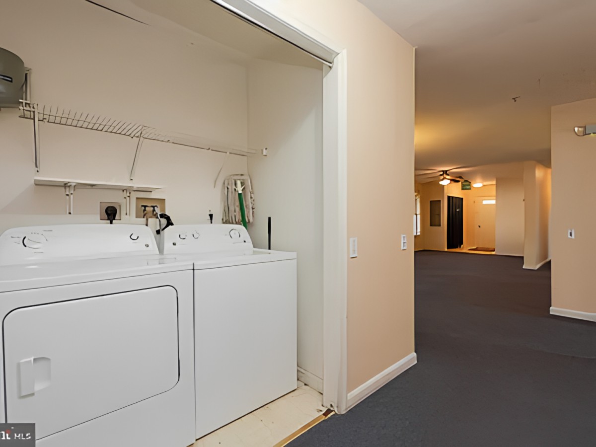 A small laundry area in an apartment hallway featuring a washer and dryer.