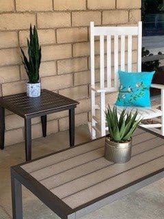 Cozy patio setup with a rocking chair, tables, and potted plants.