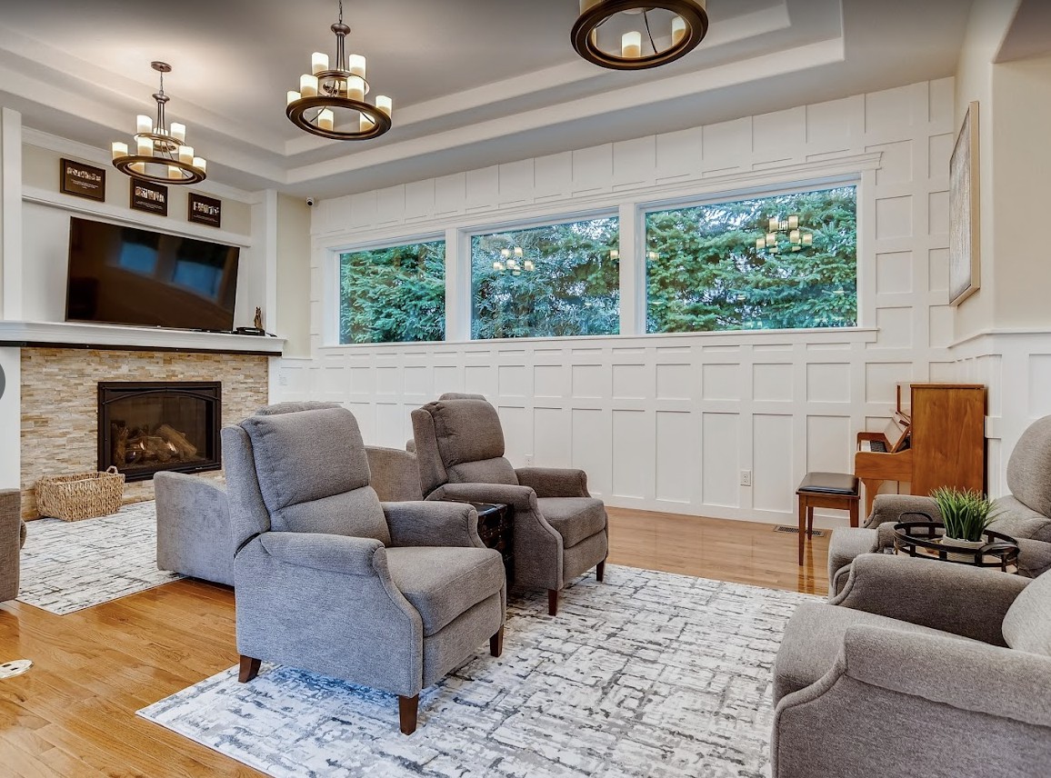 A cozy living room featuring modern recliner chairs, a fireplace, and large windows that provide natural light.