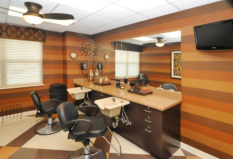 A stylish hair salon interior with comfortable chairs, large mirrors, and wood-paneled walls.