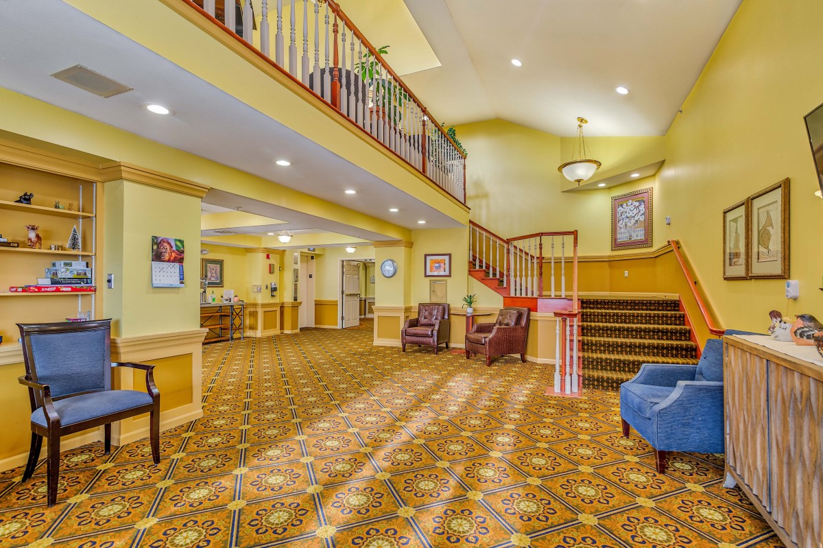A brightly lit lobby with a staircase and comfortable seating.