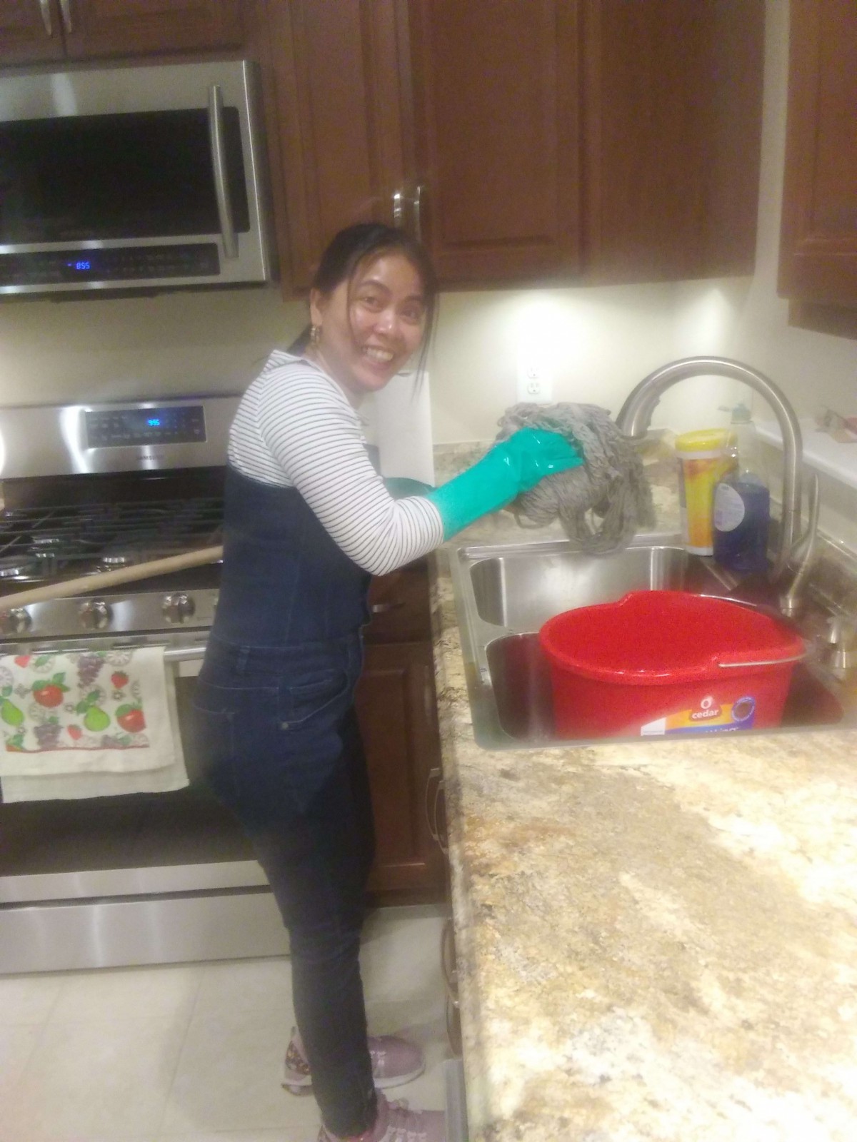 Person wearing gloves while washing dishes in the kitchen.