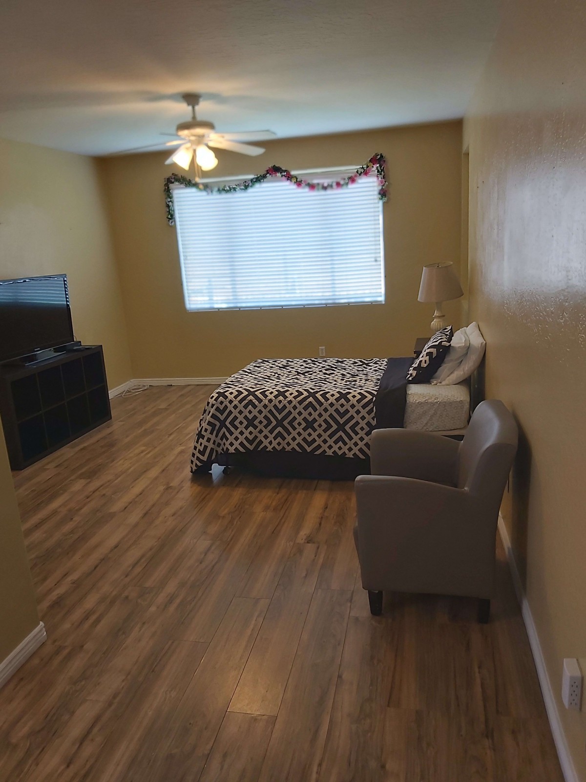 A cozy bedroom with a bed, chair, and television set.