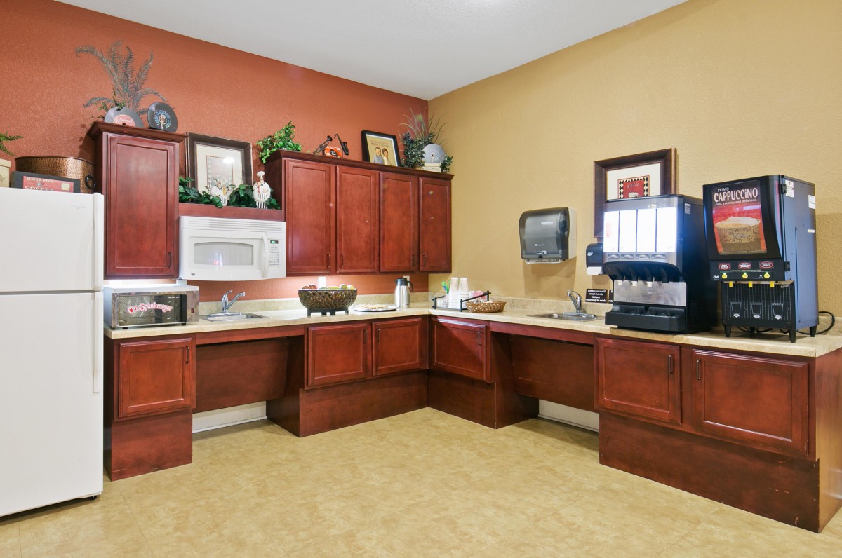 A modern kitchen area with wooden cabinets, equipped with a microwave and coffee machine.