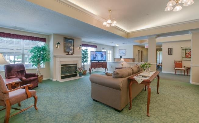A spacious living room featuring a fireplace, comfortable seating, a large television, and decorative plants.