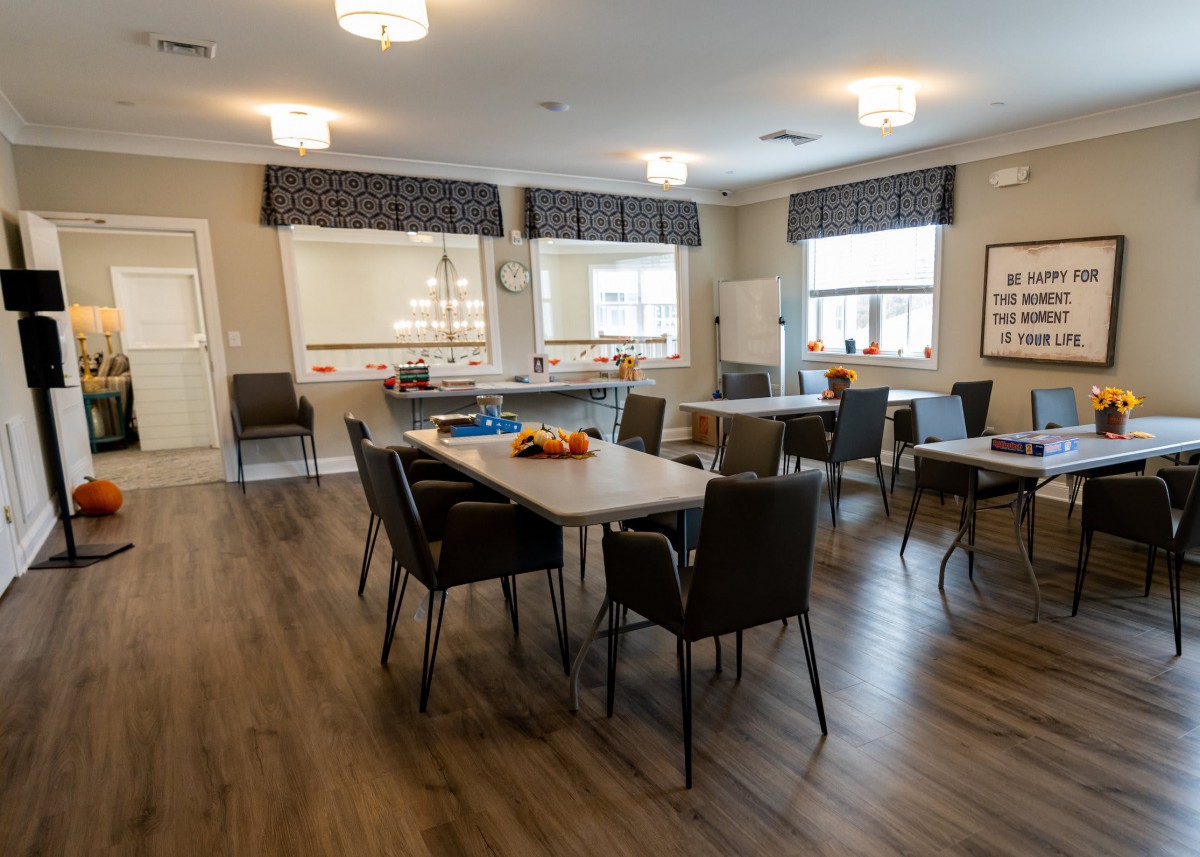 A modern dining area with tables and chairs, featuring large windows and stylish lighting.