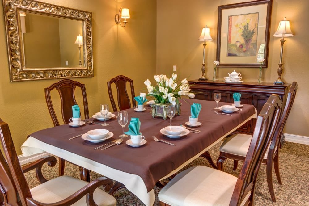 An elegantly set dining table with a floral centerpiece, surrounded by classic wooden chairs.