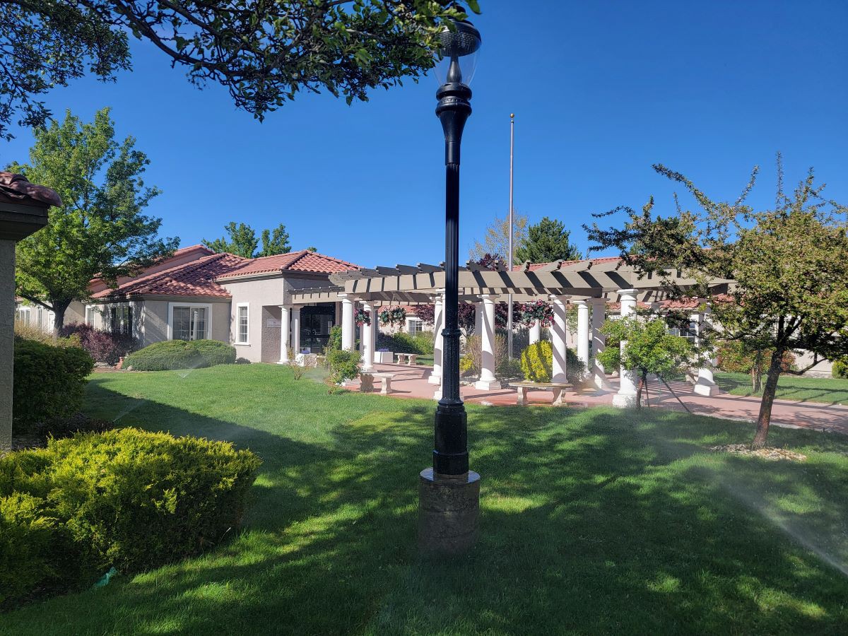 A beautiful house with a lush green garden and a classic lamp post under a clear blue sky.