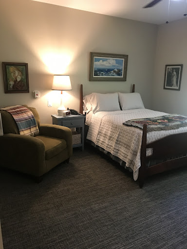 A cozy bedroom setup featuring a comfortable bed, an armchair, and artistic wall decor.
