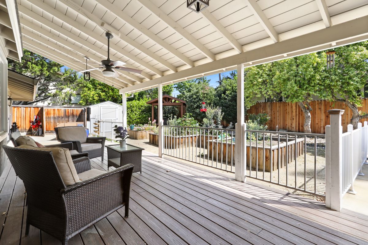 A covered patio with comfortable outdoor seating overlooking a garden.