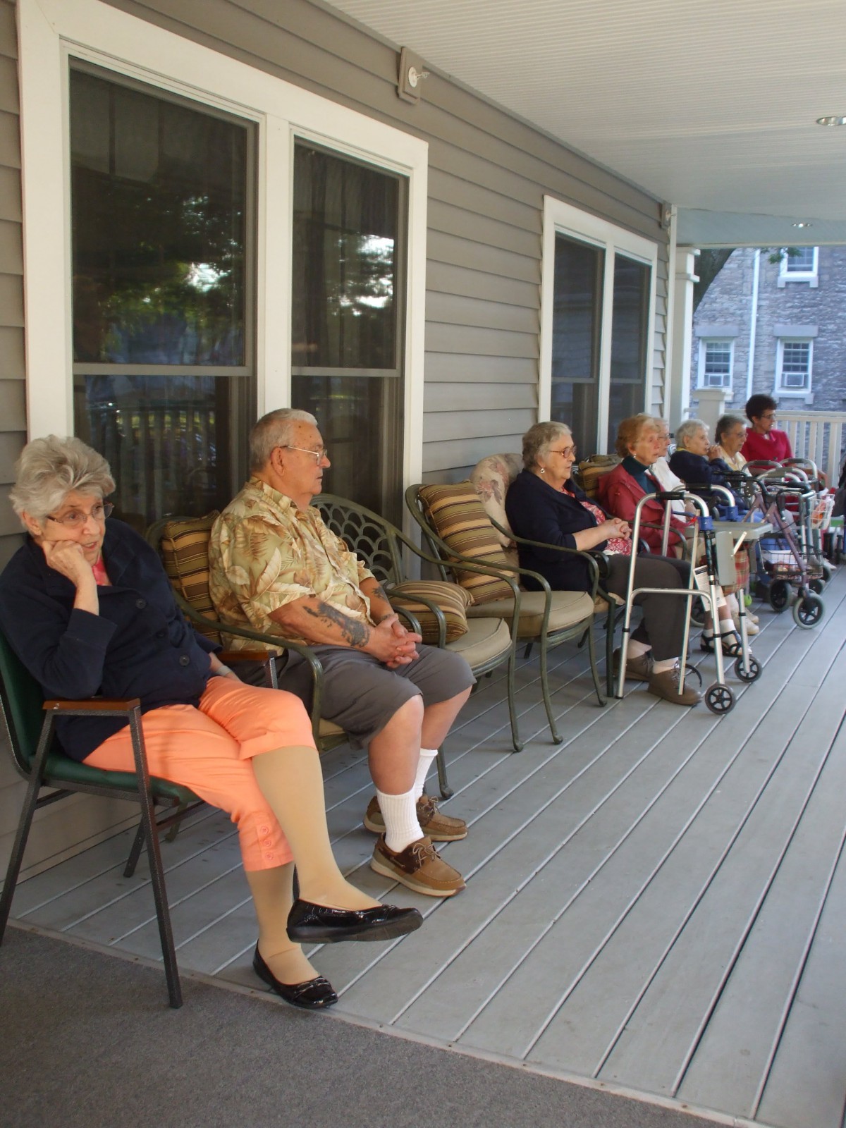 A group of elderly people sitting on a porch, enjoying a calm afternoon.