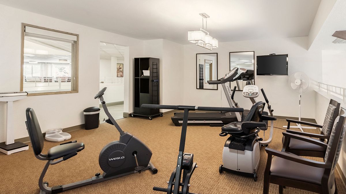 A small fitness room equipped with a treadmill, stationary bike, and other exercise machines.