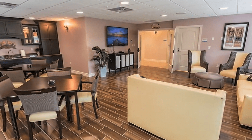 A cozy lounge area featuring comfortable seating, a wall-mounted television, and stylish wood flooring.