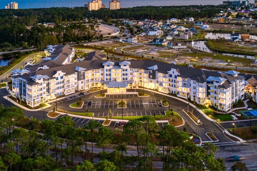 Aerial view of a well-lit residential apartment complex during twilight.