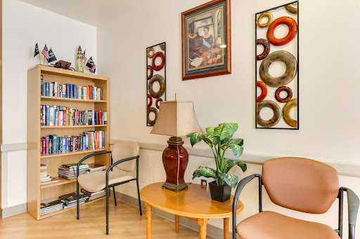 A cozy corner of a living room featuring a bookshelf, decorative artwork, and comfortable seating.