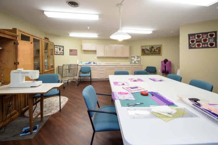 A well-lit craft room with tables and chairs, equipped for sewing activities.