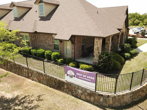 A well-maintained residential home with a decorative fence and lush landscaping.