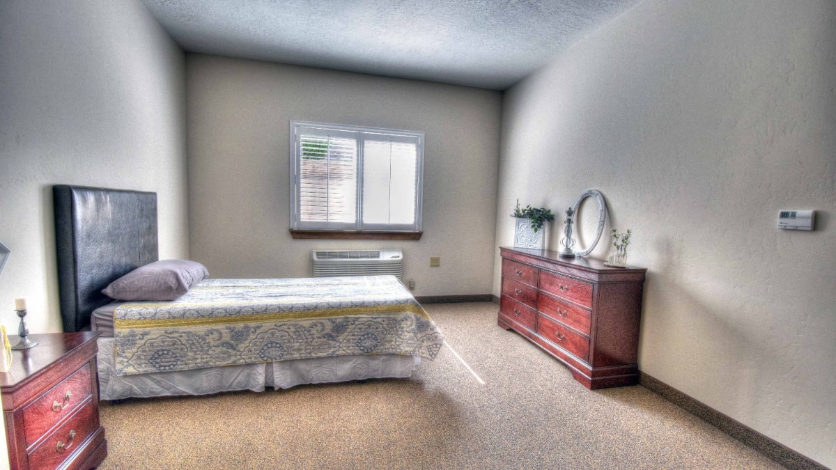A minimalist bedroom with a single bed and a wooden dresser.