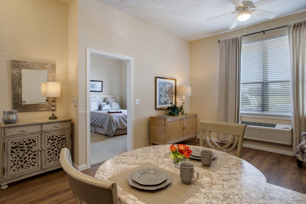 A cozy dining area with a table set for two, featuring a view into the adjacent bedroom.