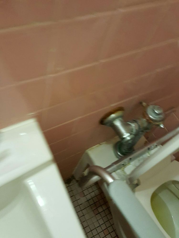 A bathroom with a toilet and sink featuring pink tiled walls.