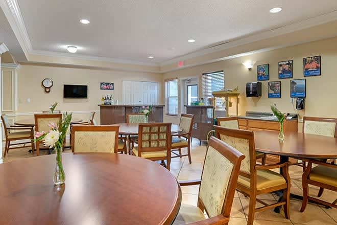 An indoor dining area with neatly arranged tables and chairs, decorated with simple decor and illuminated by ceiling lights.