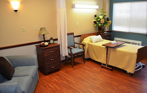 A cozy hospital room featuring a bed, seating area, and decorative elements.