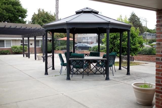 A metal gazebo with a table and chairs in a paved backyard area.