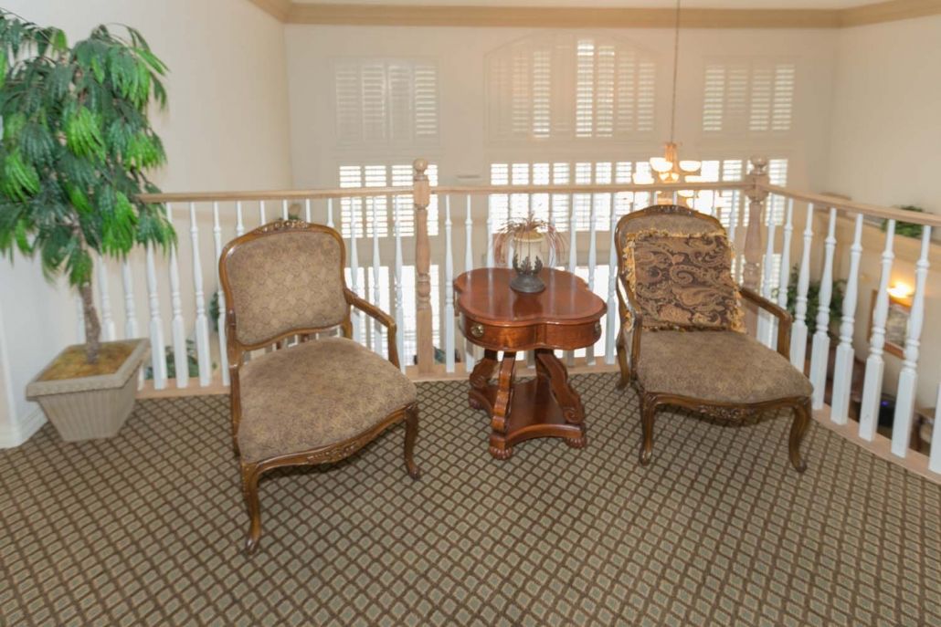 Two ornate chairs and a wooden table in a sunlit living room.
