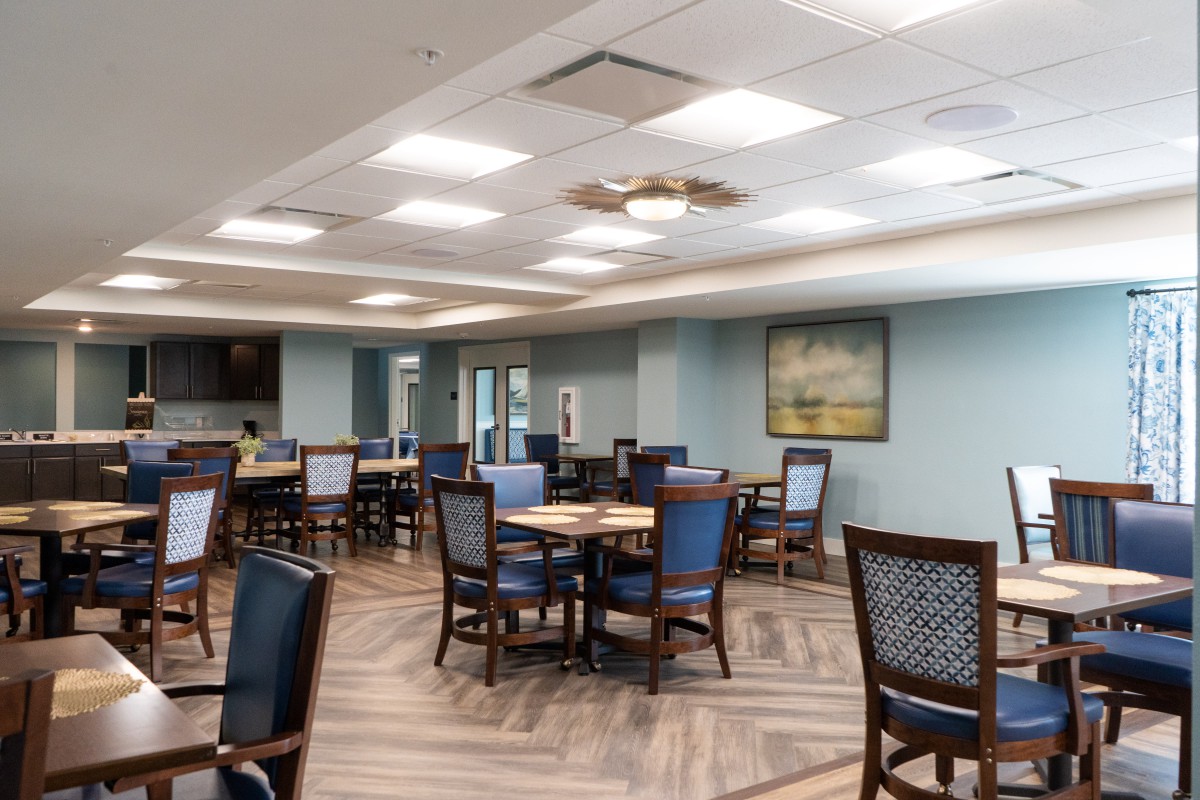 A neatly arranged dining area with multiple tables and chairs, well-lit with overhead lights.