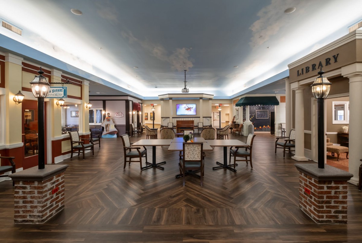 A spacious dining area with elegant decor, featuring wooden floors, tables, and chandeliers.
