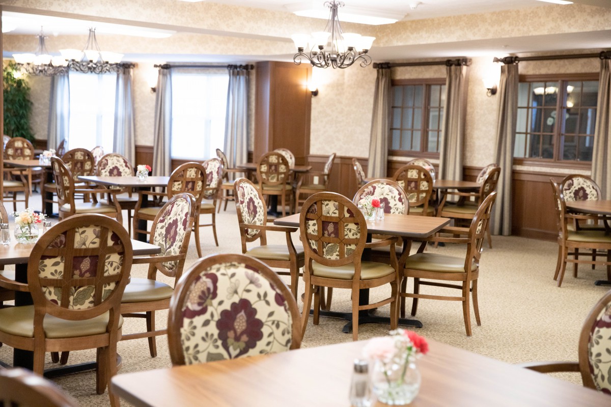 An elegantly decorated indoor dining area with wooden tables and floral-patterned chairs.