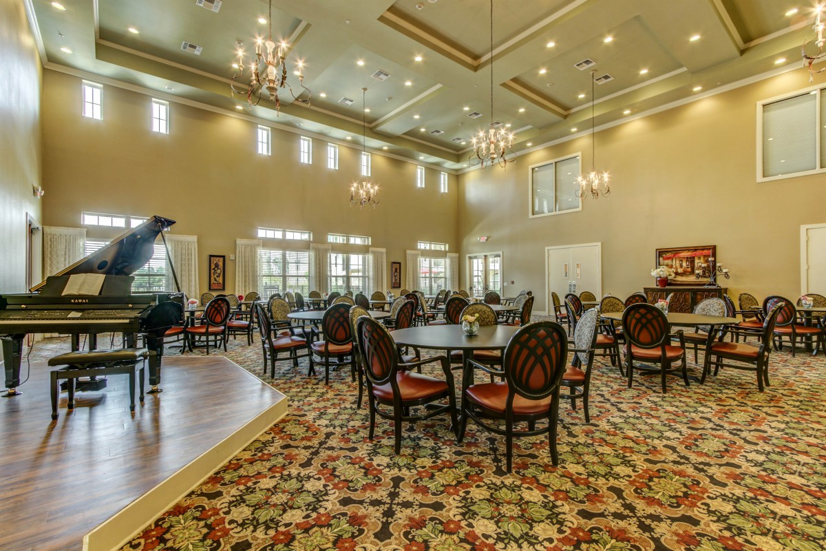 Spacious and elegant dining area with chandeliers and round tables.