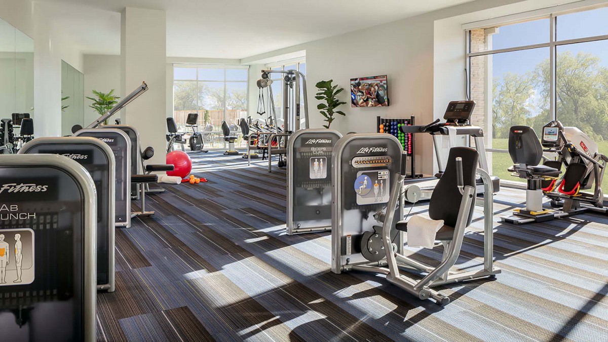 A modern gym with various exercise equipment and cardio machines.
