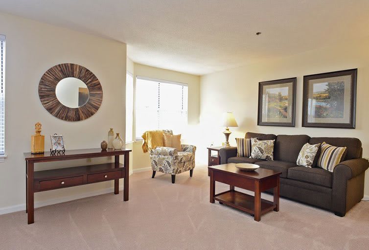 A cozy living room with a sofa, coffee table, and decorative elements like a mirror and artwork on the walls.