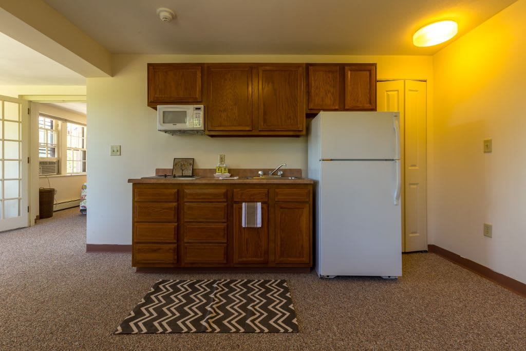 Small apartment kitchen with wooden cabinets and appliances.