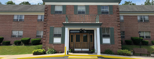 A brick building featuring a welcoming entrance with wooden doors and green shutters.