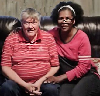 Two people sitting on a couch, smiling at the camera.
