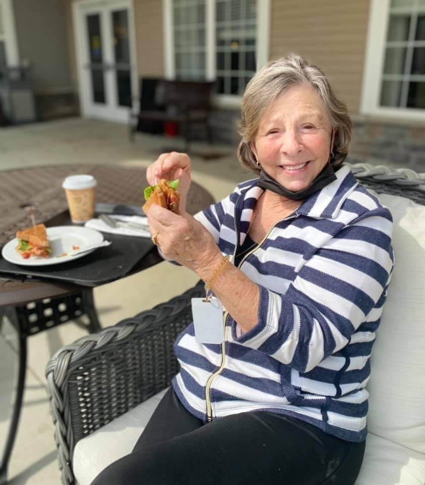 A woman enjoying a meal with coffee while seated outdoors.