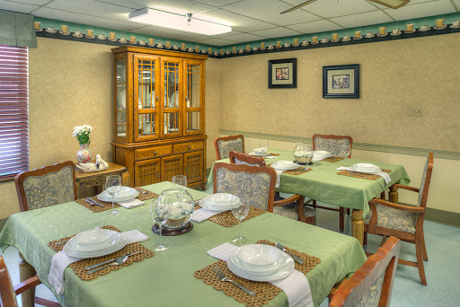 A well-arranged dining room featuring green table settings and a wooden cabinet.