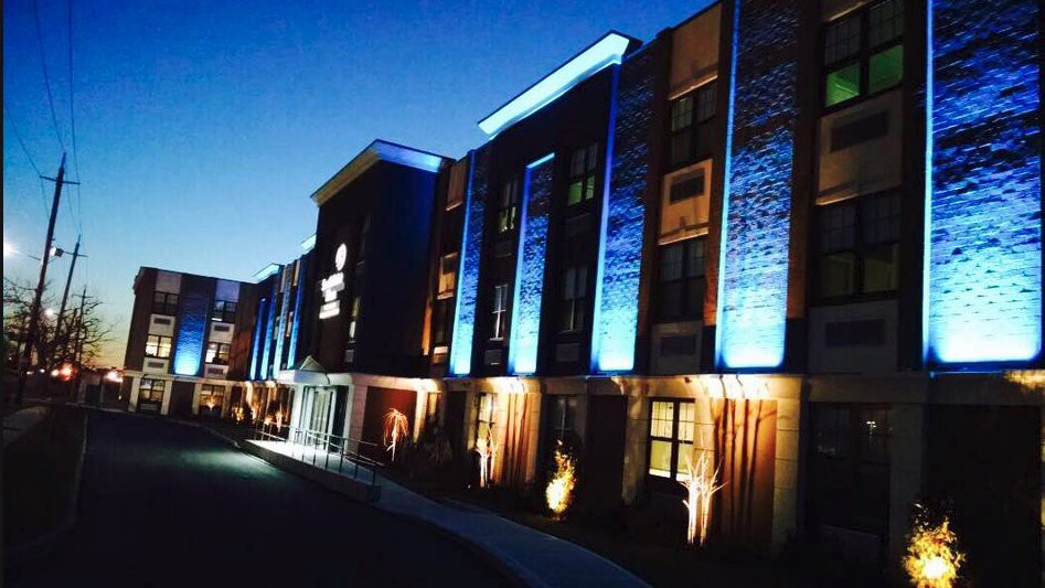 A hotel building illuminated with vibrant lights against a dusky sky.
